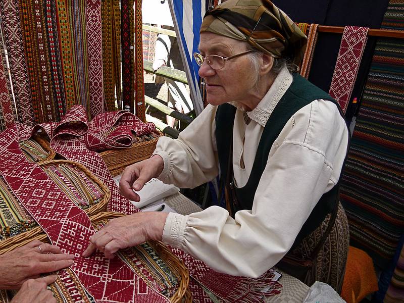 Woman telling the story of the Lielvarde belt.<br />Arts and crafts fair at the Latvian Ethnographic Open Air Museum.<br />June 4, 2011 - Riga, Latvia.