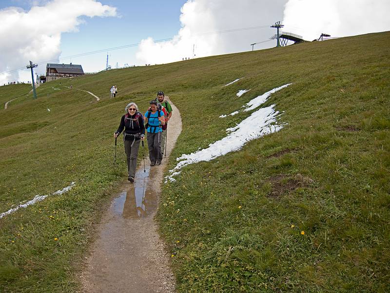 Joyce, Melody, and Sati on the trail. By the way, that is fresh snow by the side of the trail.<br />Seceda cable car terminal in back.<br />Hike from Seceda cable car terminal to Puez hut.<br />July 26, 2011 - NE of St. Ulrich/Ortisei, Italy.